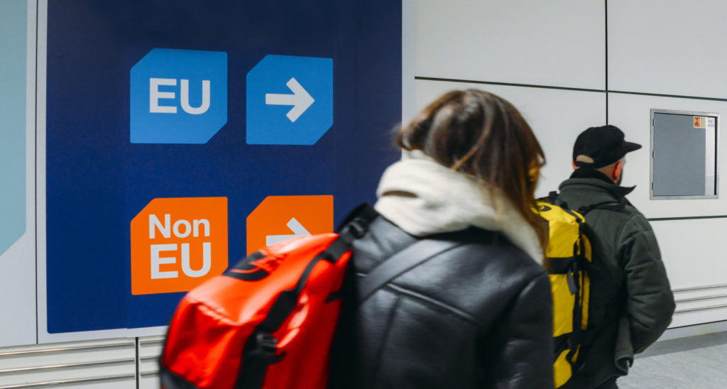 Passengers walks past sign prior to immigration control pass a si