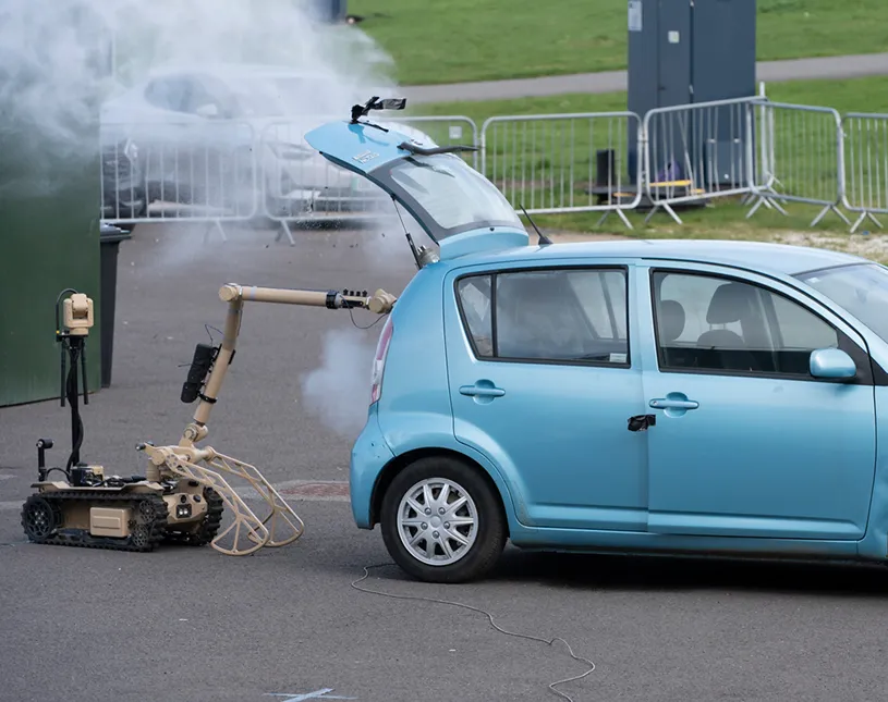 A remotely operated robot beside a car during an outdoor counter-threat demonstration.