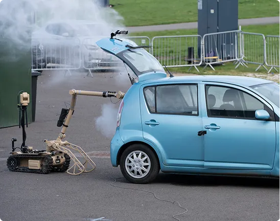 A remotely operated robot beside a car during an outdoor counter-threat demonstration.